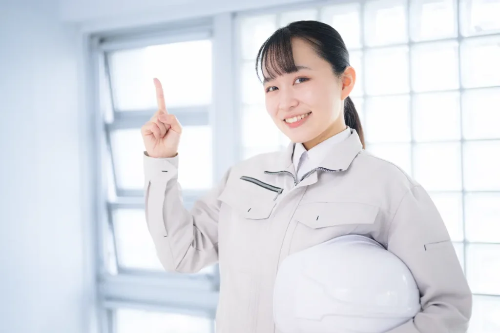 A-woman-in-work-clothes-makes-eye-contact-with-the-camera,-pointing-to-recommend-or-highlight-something