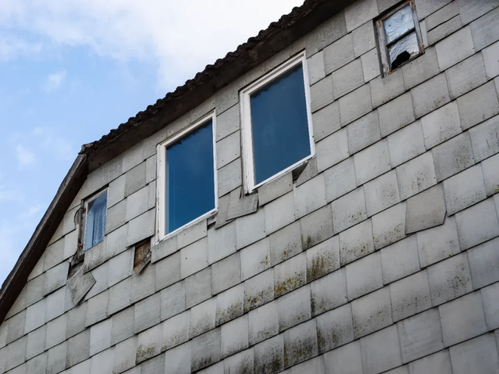 アスベスト板で覆われた建物のファサード。古い家の外壁が損傷している。