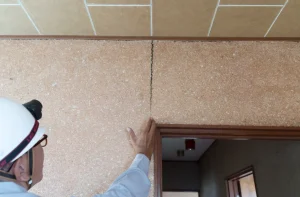 地震で亀裂が入った壁を調査するビジネスマン