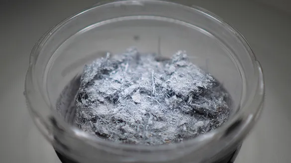 アルフレッド株式会社の調査・分析サービスにて取り扱うアスベストの検体試料。建物から採取されたサンプルを分析容器に入れ、精密な石綿含有調査を行う前の状態。