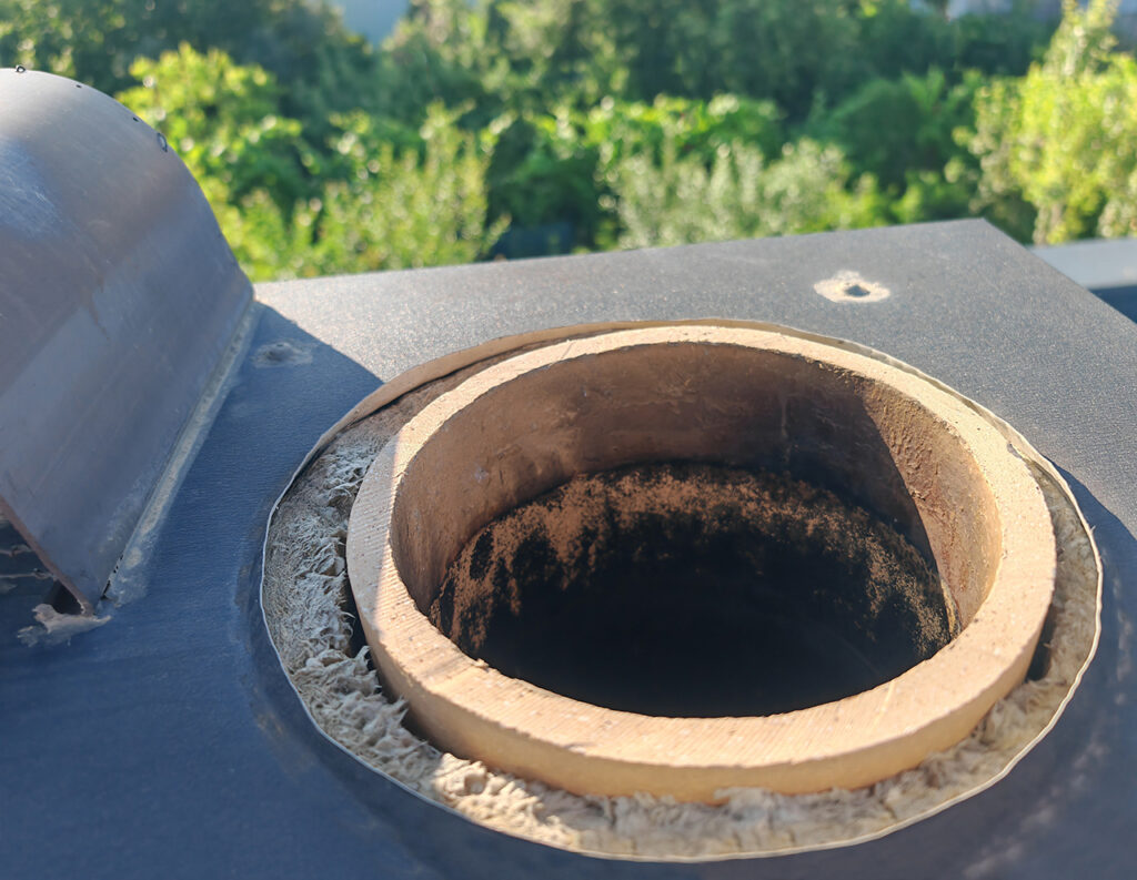 内部には黒い煤が付着していることが確認できる断熱材に囲まれた二重構造の煙突の開口部