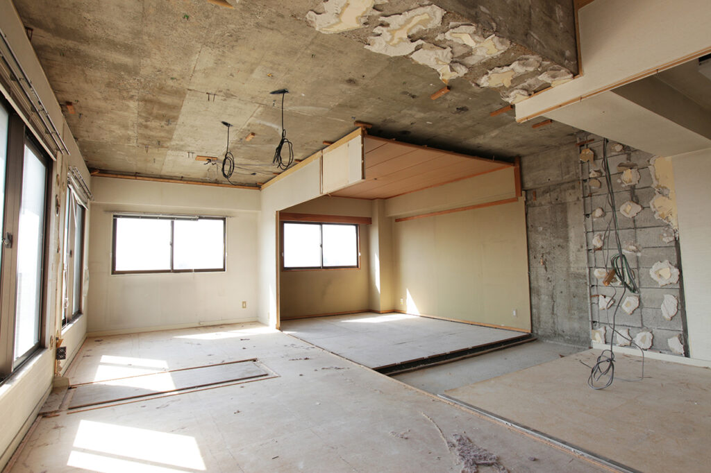 リフォームや解体工事が始まった室内の様子。天井や壁の一部が剥がされ、コンクリート下地や接着剤の跡が露出しており、アスベスト事前調査が必要な段階の現場風景