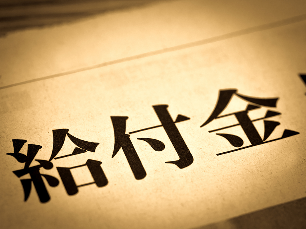 紙に、黒い文字で『給付金』と縦書きで大きく印字され、その部分がライトアップされている。
