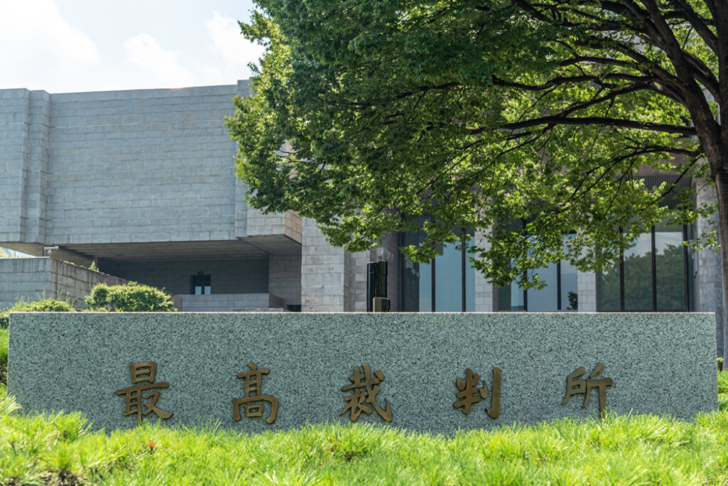 最高裁判所の建物の前に建つ石碑。石碑には金色の文字で『最高裁判所』と刻まれている。