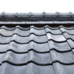 建物の屋根を斜め上から俯瞰で捉えた写真。均一に並んだスレート瓦（カラーベスト・コロニアル等）が広範囲に映っており、屋根材の全体的な配置と色あせなどの経年劣化の状態が確認できる。