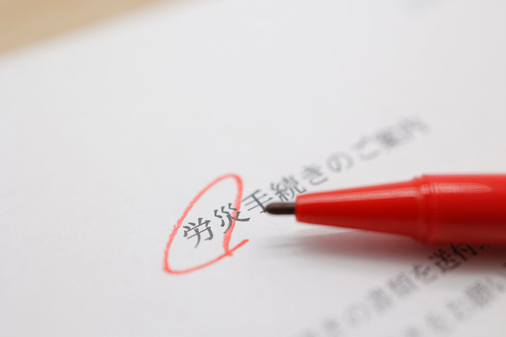 「労災手続きのご案内」と書かれた書類の「労災」の文字に赤ペンで丸がついている。